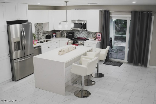 kitchen featuring a breakfast bar, sink, decorative light fixtures, a center island, and stainless steel appliances