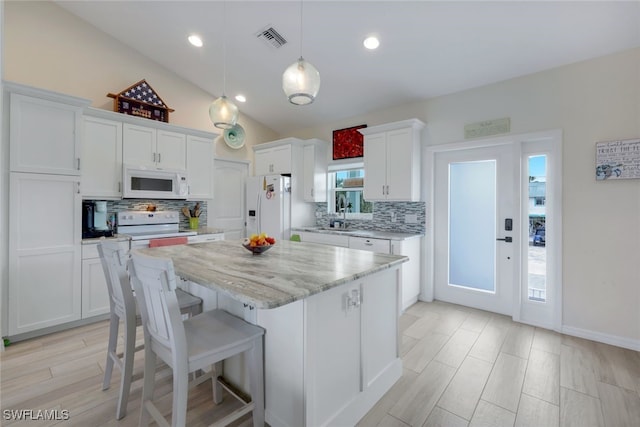 kitchen featuring pendant lighting, white cabinets, tasteful backsplash, white appliances, and a center island