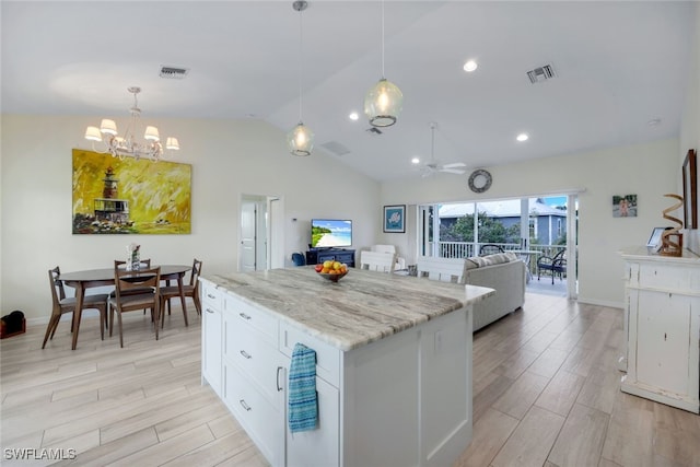 kitchen featuring white cabinets, a center island, light stone counters, and pendant lighting