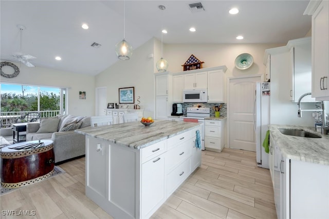 kitchen with a center island, white appliances, white cabinets, decorative light fixtures, and lofted ceiling