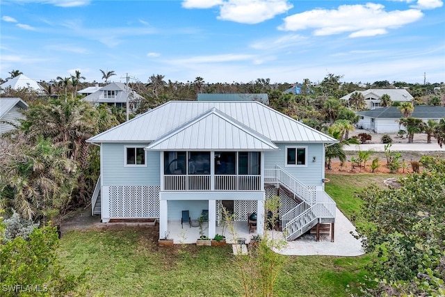 rear view of property with a sunroom, a patio area, and a lawn