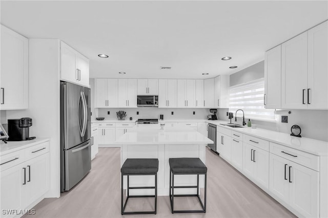 kitchen featuring sink, a breakfast bar area, white cabinetry, a center island, and stainless steel appliances