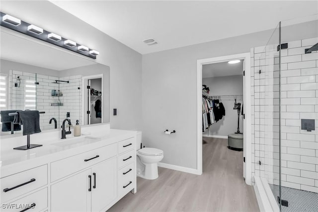 bathroom with vanity, wood-type flooring, a shower with door, and toilet