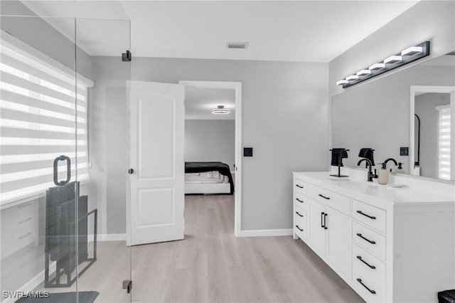 bathroom with vanity, wood-type flooring, a healthy amount of sunlight, and a shower with shower door