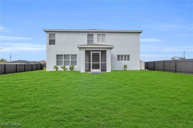 rear view of house featuring a yard and a sunroom