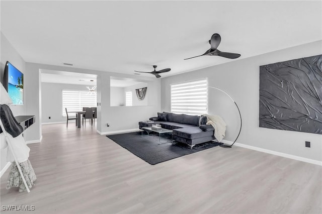 living room featuring ceiling fan, light hardwood / wood-style floors, and a wealth of natural light