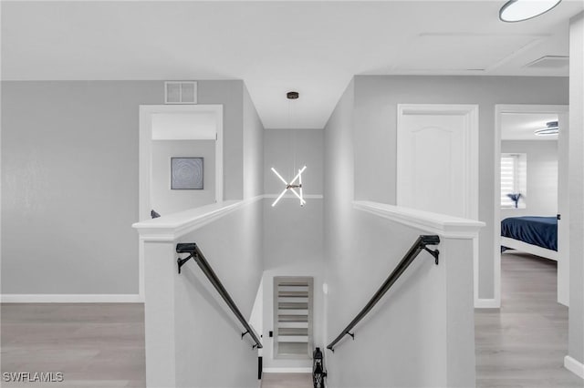 stairway featuring an inviting chandelier and hardwood / wood-style flooring