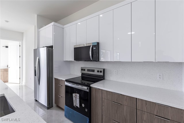 3005 28th St SW, Lehigh Acres, FL 33976 - kitchen with stainless steel appliances, modern cabinets, white cabinets, backsplash, and light stone counters