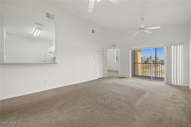 unfurnished living room featuring carpet floors, ceiling fan, and a high ceiling