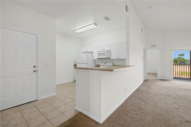 kitchen with white cabinetry, light tile patterned floors, white appliances, and kitchen peninsula