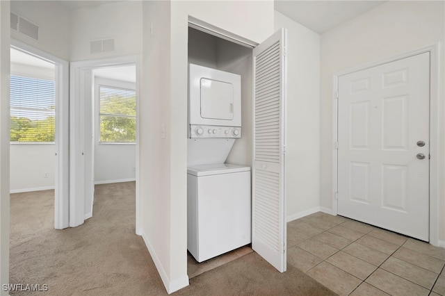 clothes washing area featuring stacked washer / dryer and light carpet