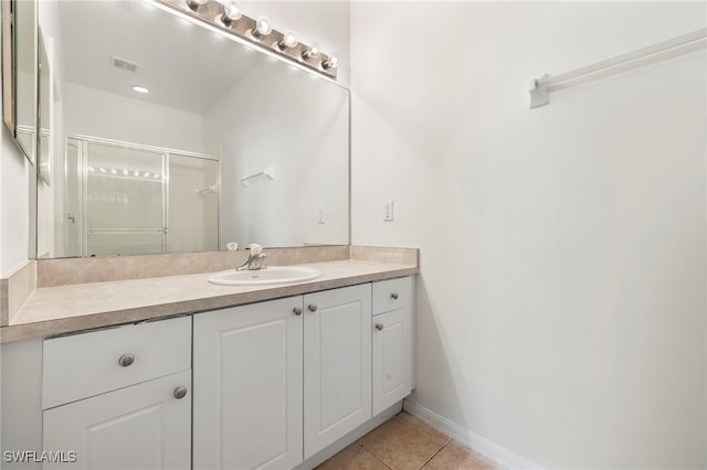 bathroom featuring tile patterned floors, a stall shower, baseboards, visible vents, and vanity