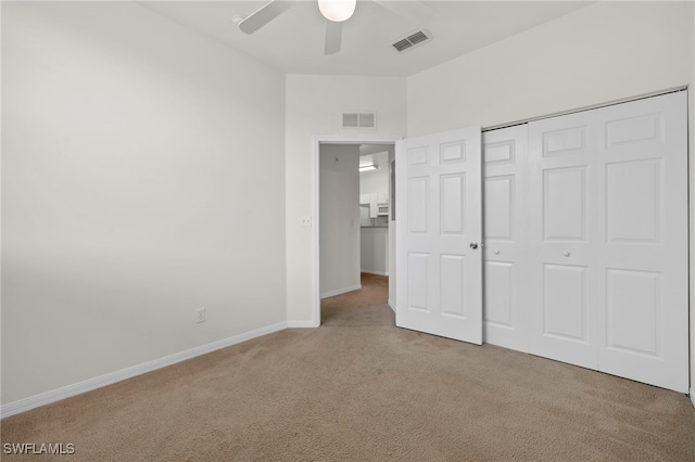 unfurnished bedroom featuring light colored carpet, ceiling fan, and a closet