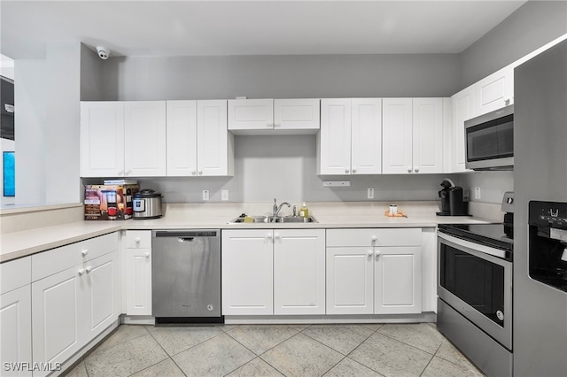 kitchen with white cabinetry, stainless steel appliances, light tile patterned flooring, and sink