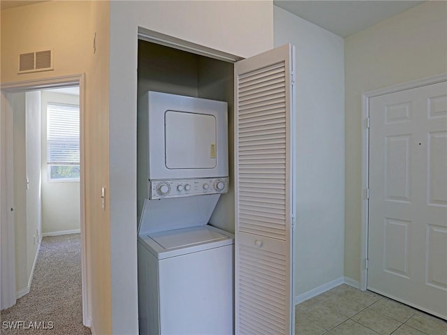 clothes washing area with visible vents, baseboards, stacked washer and clothes dryer, and laundry area