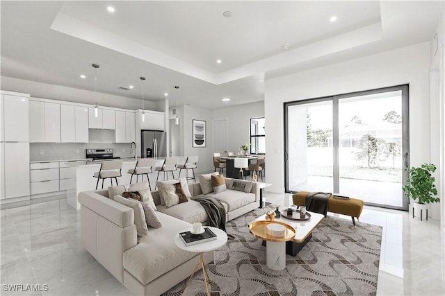 living room featuring sink and a tray ceiling