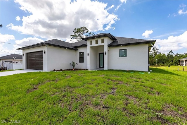 prairie-style home featuring stucco siding, driveway, a garage, and a front lawn