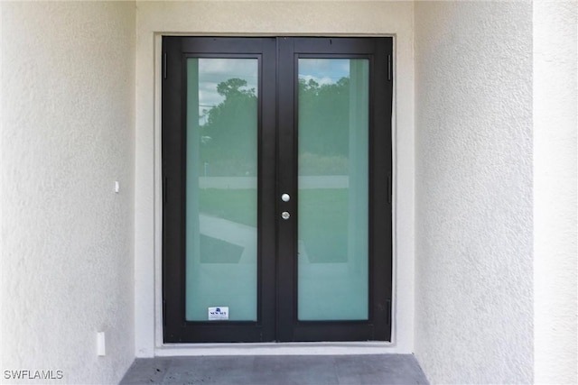view of exterior entry featuring stucco siding and french doors