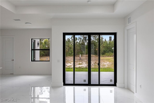 entryway with light marble finish flooring, a tray ceiling, and baseboards