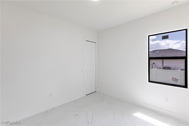 unfurnished room with marble finish flooring and baseboards