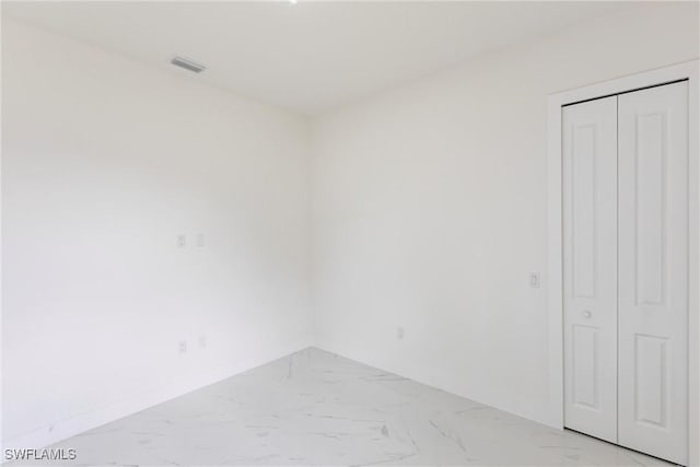 unfurnished room featuring light marble finish floors and baseboards