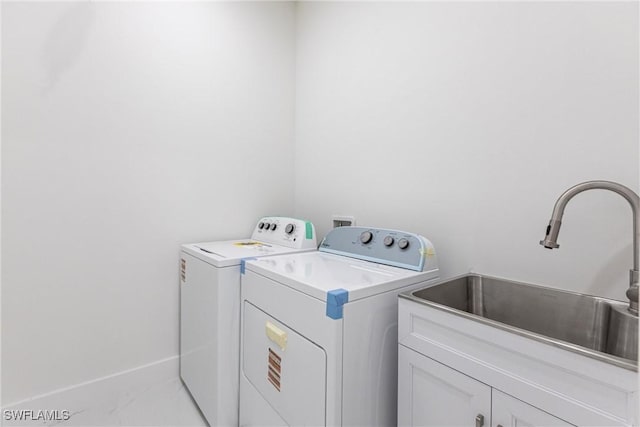 clothes washing area featuring washing machine and dryer, cabinet space, and baseboards