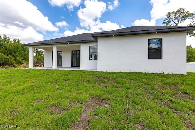 back of house featuring stucco siding, a lawn, and a patio area
