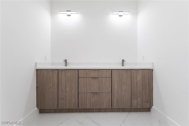 bathroom with double vanity, baseboards, and marble finish flooring