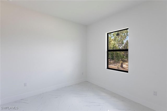 empty room featuring marble look tiles and baseboards