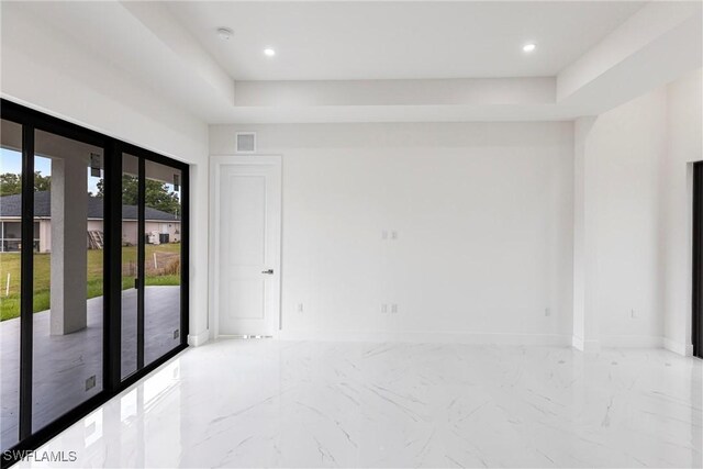 unfurnished room featuring marble tiled flooring, baseboards, a raised ceiling, and recessed lighting