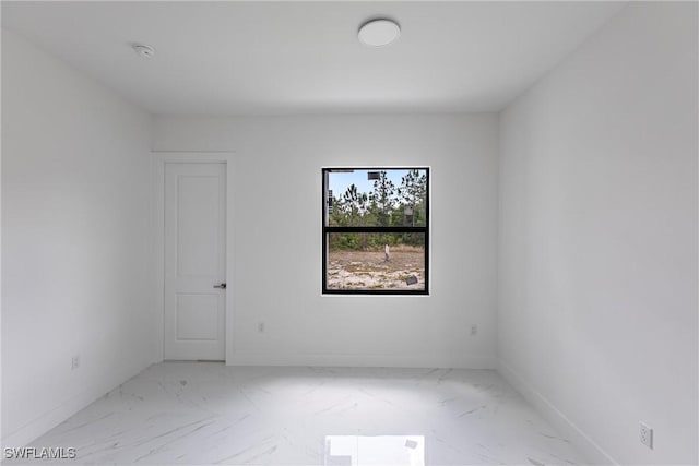 unfurnished room with marble finish floors, baseboards, and a smoke detector