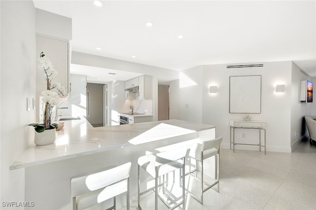 kitchen featuring white cabinetry, kitchen peninsula, and sink