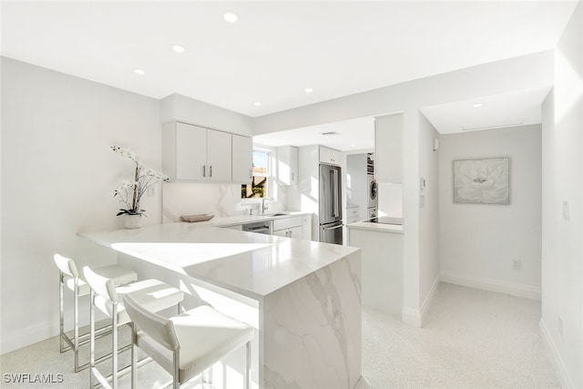 kitchen with stainless steel appliances, a breakfast bar, white cabinets, and kitchen peninsula