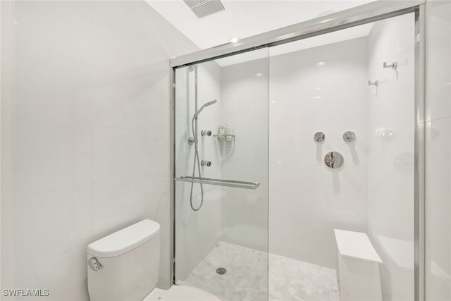 bathroom featuring tile walls, a shower with door, and toilet