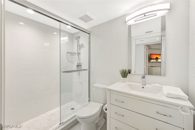 bathroom with vanity, a shower with shower door, tile walls, and toilet