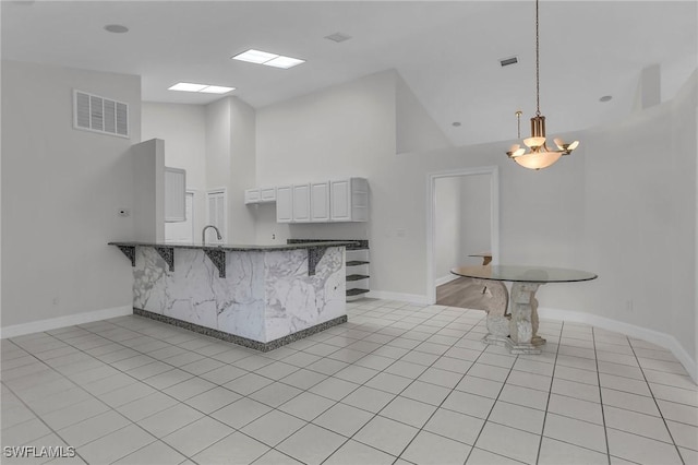 kitchen featuring a breakfast bar, visible vents, a peninsula, and light tile patterned floors