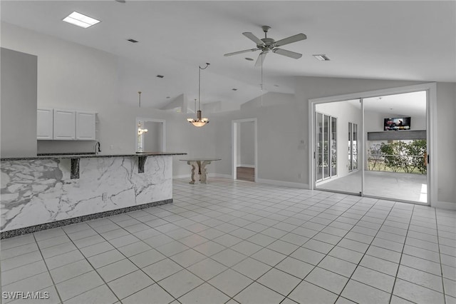 unfurnished living room featuring ceiling fan with notable chandelier, light tile patterned flooring, lofted ceiling, and visible vents