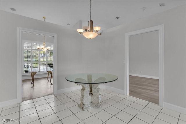 dining area with an inviting chandelier, baseboards, light tile patterned floors, and visible vents