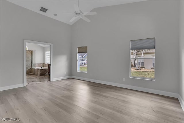 unfurnished bedroom with high vaulted ceiling, ensuite bath, baseboards, and wood finished floors