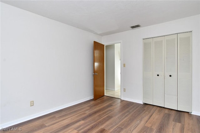 unfurnished bedroom with a closet and dark hardwood / wood-style floors