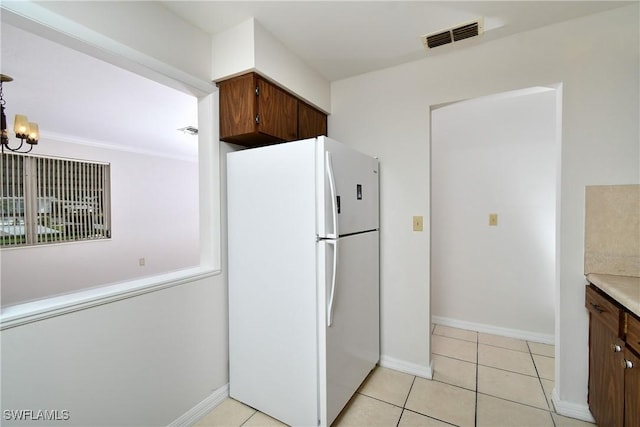 kitchen featuring light tile patterned floors, white refrigerator, and a chandelier