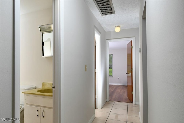 hallway featuring a textured ceiling and light tile patterned floors