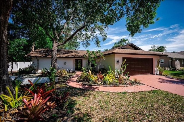 ranch-style house with a garage, concrete driveway, fence, and stucco siding