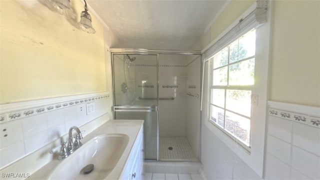 bathroom with tile patterned flooring, vanity, tile walls, and an enclosed shower