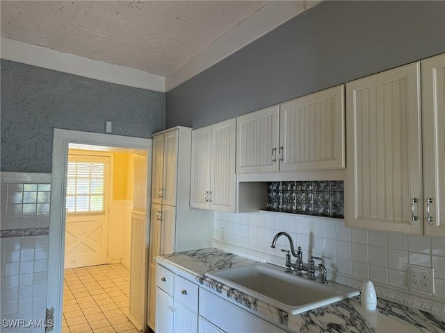 kitchen with light tile patterned flooring, sink, a textured ceiling, decorative backsplash, and white cabinets