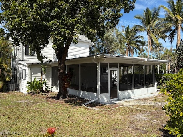 back of house featuring a sunroom, a yard, and central AC unit