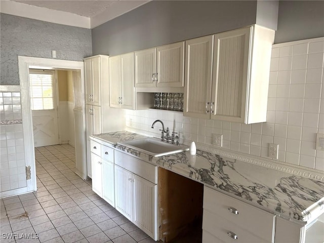 kitchen featuring sink, light tile patterned floors, backsplash, and light stone counters