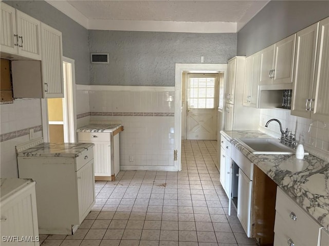 kitchen with white cabinets, sink, tile walls, and light tile patterned floors