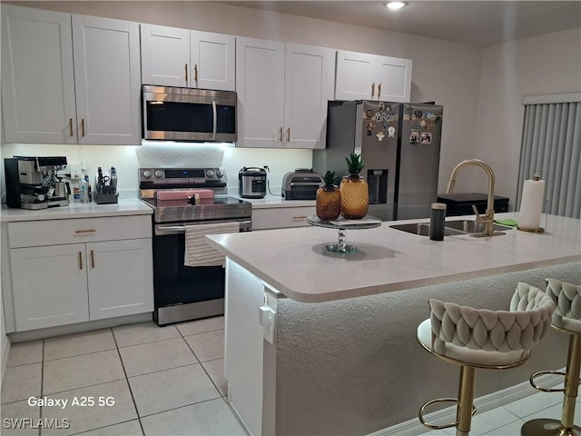 kitchen with white cabinetry, appliances with stainless steel finishes, a kitchen island with sink, and sink