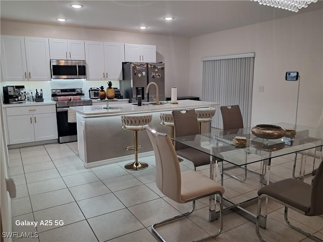 kitchen featuring stainless steel appliances, a kitchen island with sink, and white cabinets